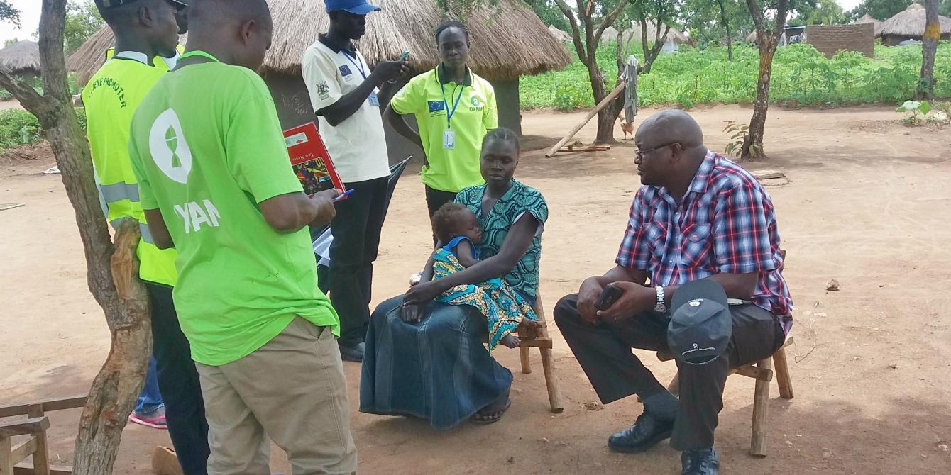 Peter Kamalingin and Oxfam staff chat with a South Sudan refugee resettled in Rhino Settlement, Ofua zone. Photo credit: Oxfam